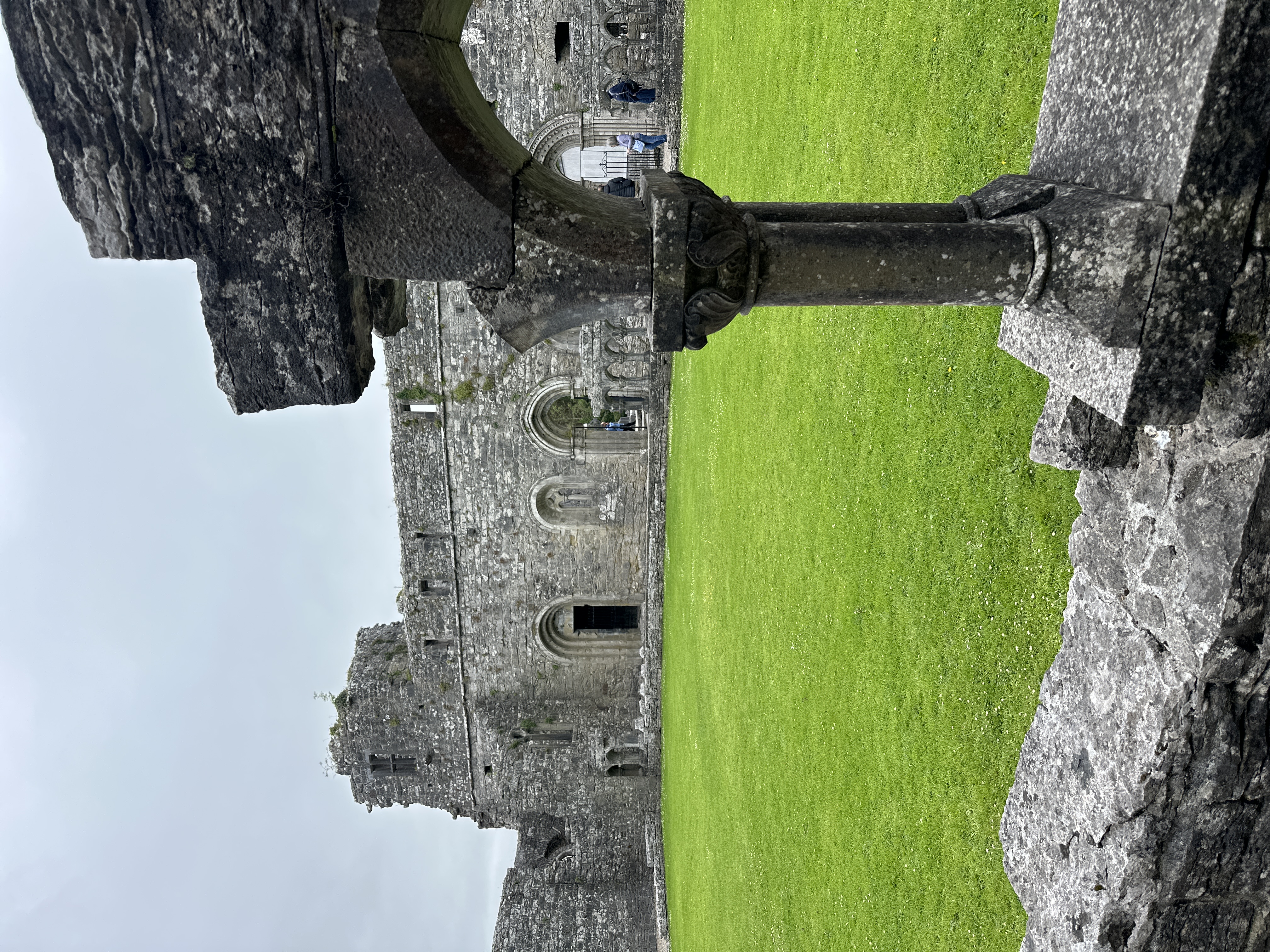 A green lawn surrounded by stone walls with arches.