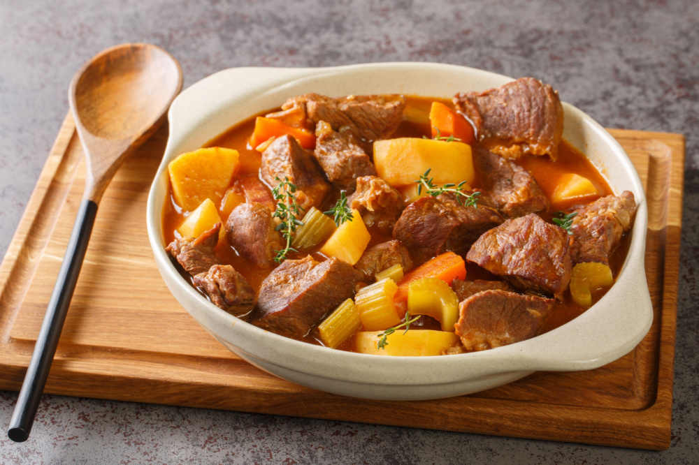 Guinness Beef Stew in a bowl with a wooden spoon.