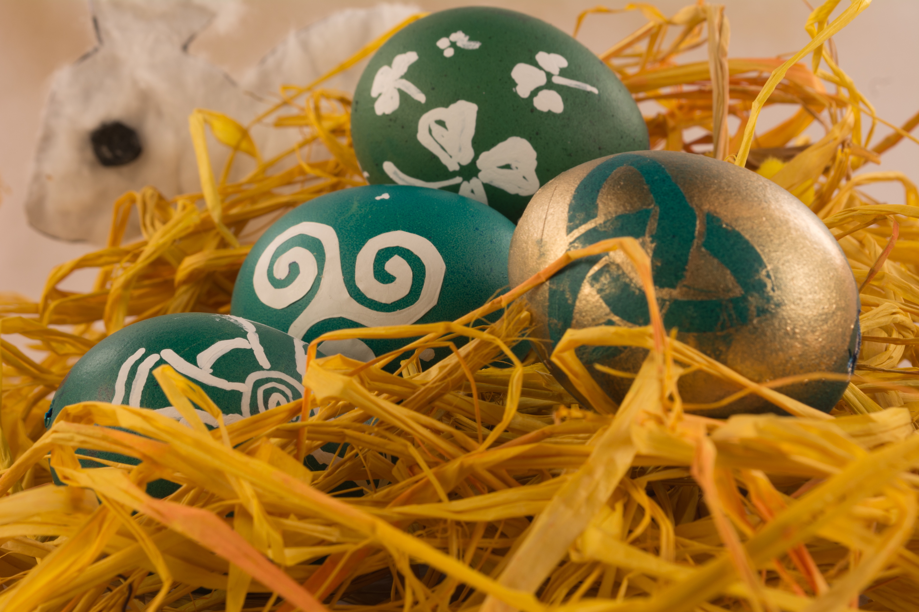 Three Easter eggs with Celtic images resting in yellow straw.