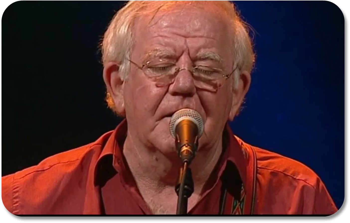 Image of middle aged man with eyes closed singing into a microphone.