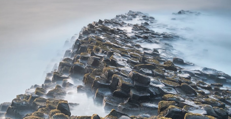 Mysterious rock formation shrouded in fog disappearing in the distance.