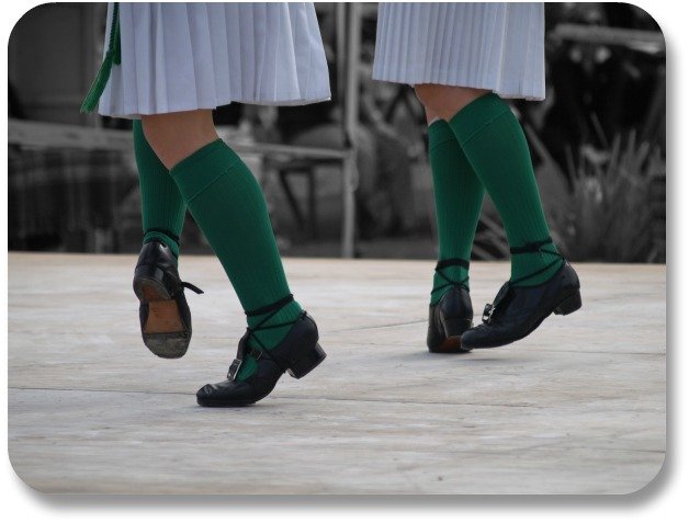 Two pairs of feet with green stockings demonstrating the Irish step dance.