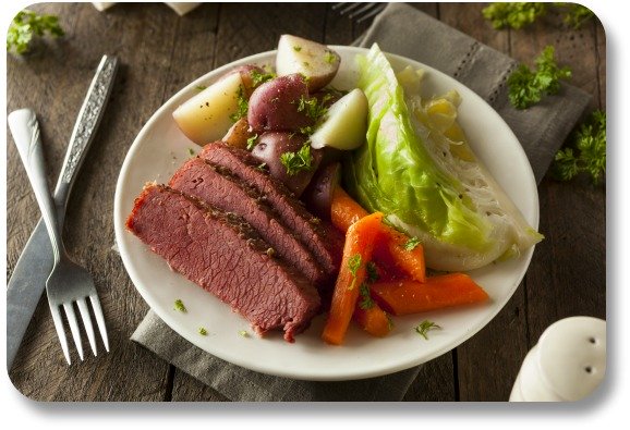 Plated corned beef and cabbage with knife and fork.