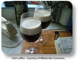 Two lovely glasses of Irish Coffee on a kitchen table next to a recipe book.