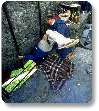 Kissing the Blarney Stone, suspended upside down with help from another man.