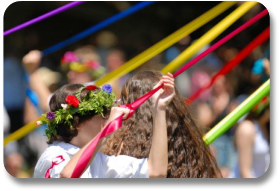 Young person performing traditional Maypole dance with colored ribbons.